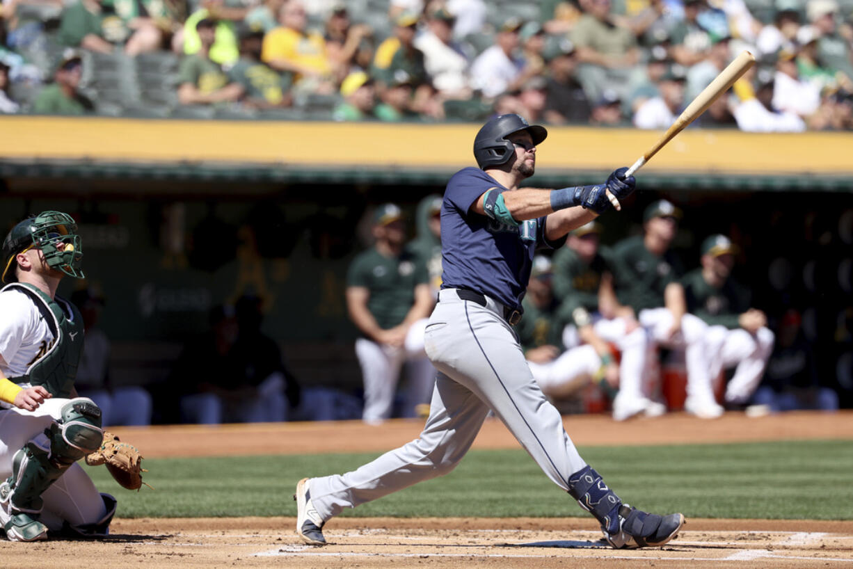 Seattle Mariners catcher Cal Raleigh, right, watches his two-run home run in front of Oakland Athletics catcher Kyle McCann, left, during the first inning of a baseball game in Oakland, Calif., Thursday, Sept. 5, 2024.