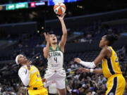 Seattle Storm guard Skylar Diggins-Smith, center, shoots as Los Angeles Sparks' Odyssey Sims, left, and Azura Stevens defend during the first half of a WNBA basketball game, Wednesday, Sept. 11, 2024, in Los Angeles. (AP Photo/Mark J.