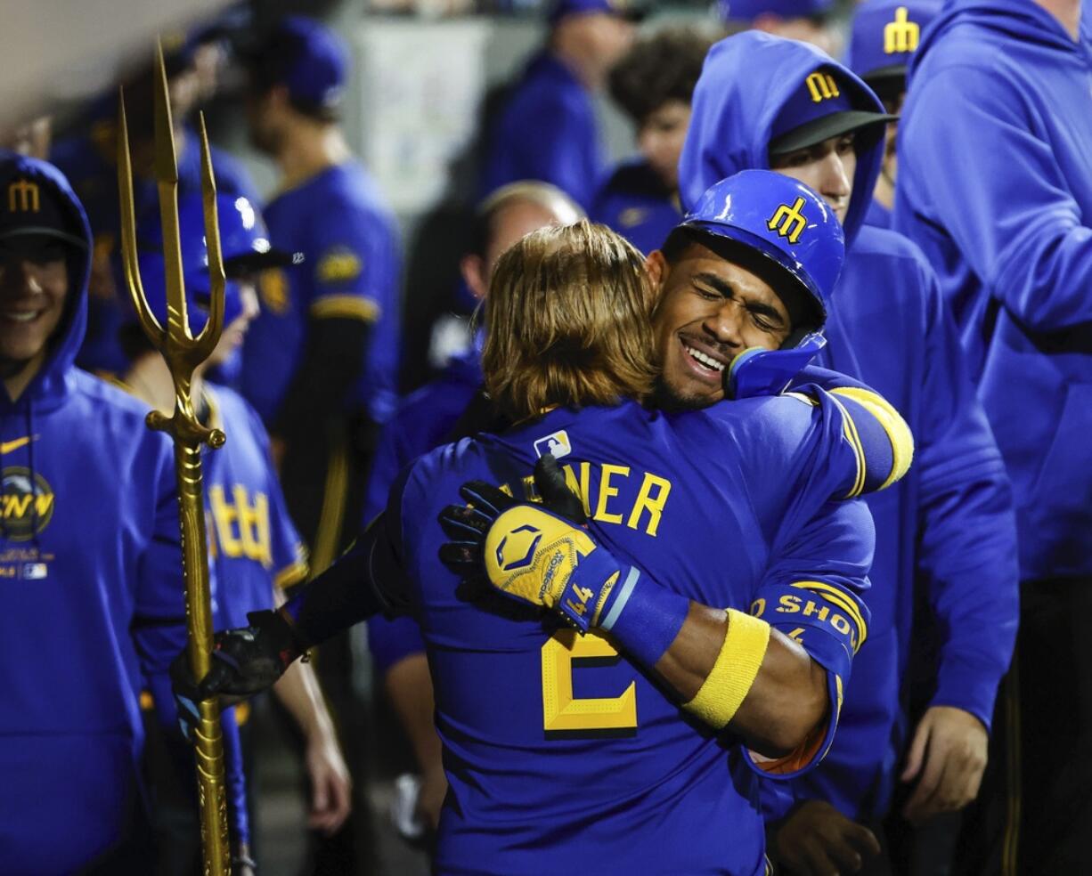 Seattle Mariners' Julio Rodriguez, right, gets a big hug from Justin Turner following his three-run homer in the eighth inning of a baseball game against the Texas Rangers, Friday, Sept.