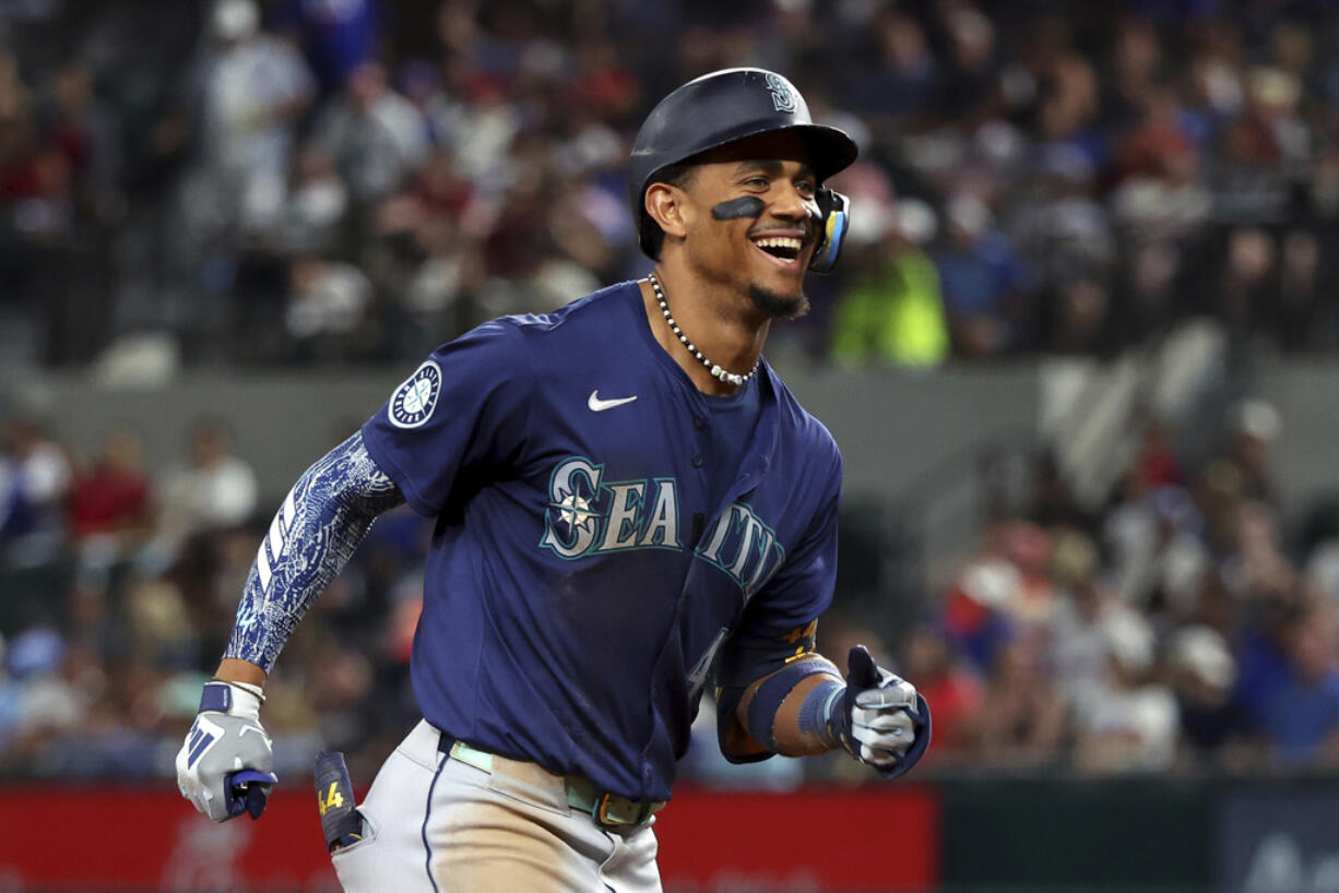 Seattle Mariners' Julio Rodriguez reacts toward the dugout as he runs the bases after hitting a two-run home run against the Texas Rangers in the seventh inning of a baseball game Friday, Sept. 20, 2024, in Arlington, Texas. (AP Photo/Richard W.