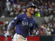 Seattle Mariners' Julio Rodriguez reacts toward the dugout as he runs the bases after hitting a two-run home run against the Texas Rangers in the seventh inning of a baseball game Friday, Sept. 20, 2024, in Arlington, Texas. (AP Photo/Richard W.