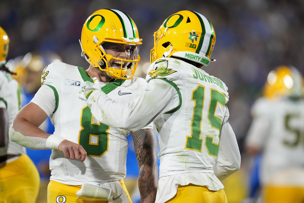 Oregon quarterback Dillon Gabriel, left, celebrates after throwing a touchdown pass to wide receiver Tez Johnson (15) during the first half of an NCAA college football game against UCLA, Saturday, Sept. 28, 2024, in Pasadena, Calif.