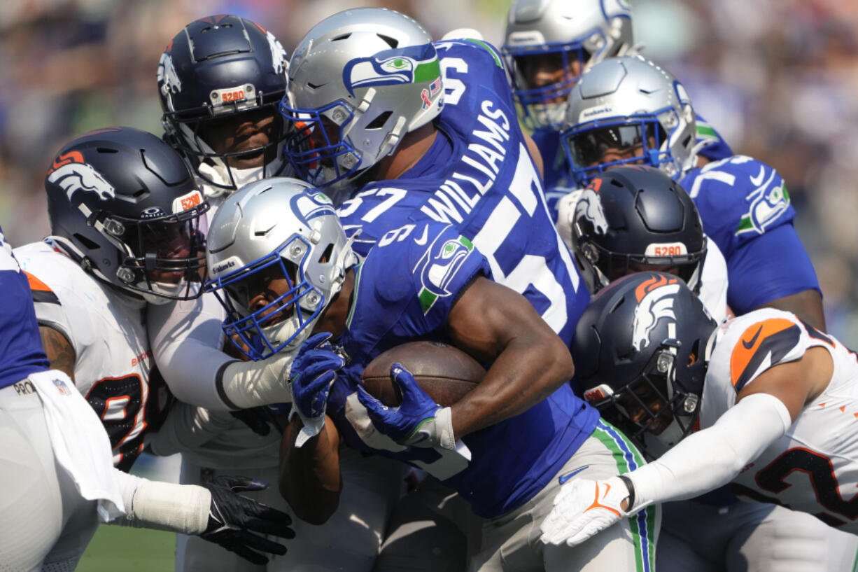 Seattle Seahawks running back Kenneth Walker III (9) is tackled by Denver Broncos players during the first half Sunday in Seattle.