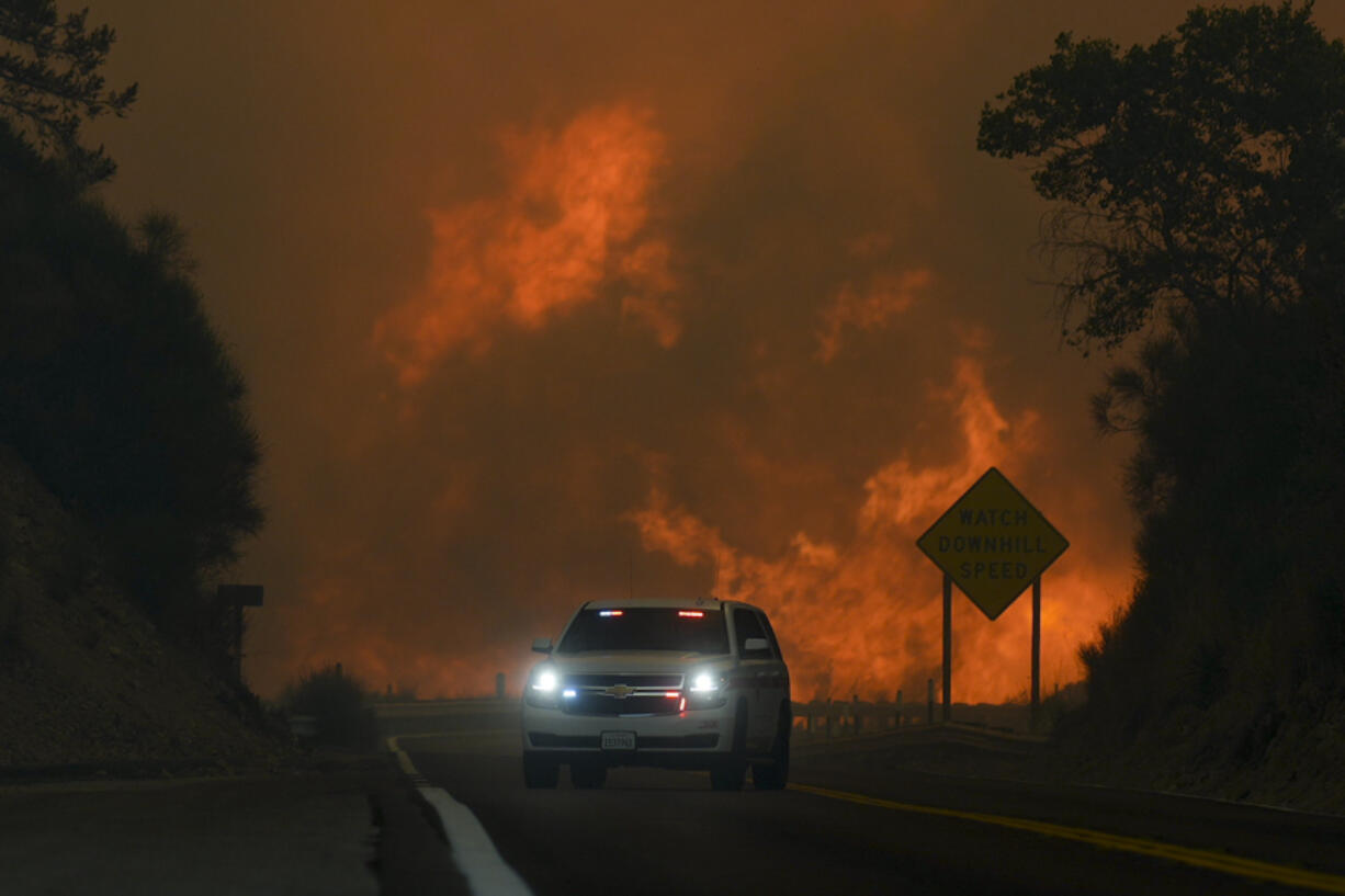 The Line Fire jumps highway 330 as an emergency vehicle is driven past Saturday, Sept. 7, 2024, near Running Springs, Calif.