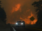 The Line Fire jumps highway 330 as an emergency vehicle is driven past Saturday, Sept. 7, 2024, near Running Springs, Calif.