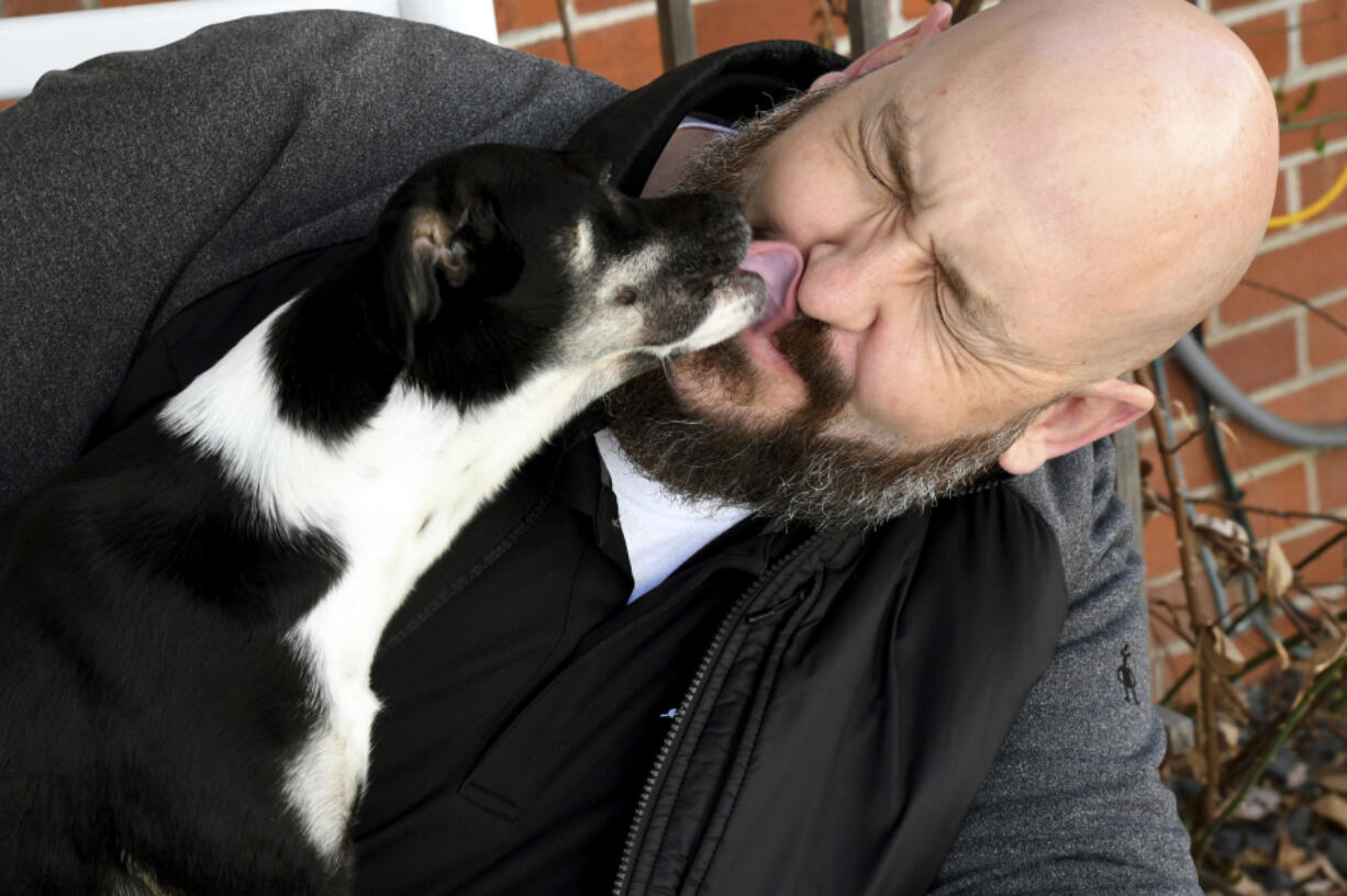 Ben Cochell, a volunteer for PAWsitive Recovery, lets his foster dog Dexter lick his face March 26 at his home in Denver.