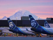 FILE - Alaska Airlines planes are shown parked at gates with Mount Rainier in the background on March 1, 2021, at Seattle-Tacoma International Airport in Seattle. (AP Photo/Ted S.