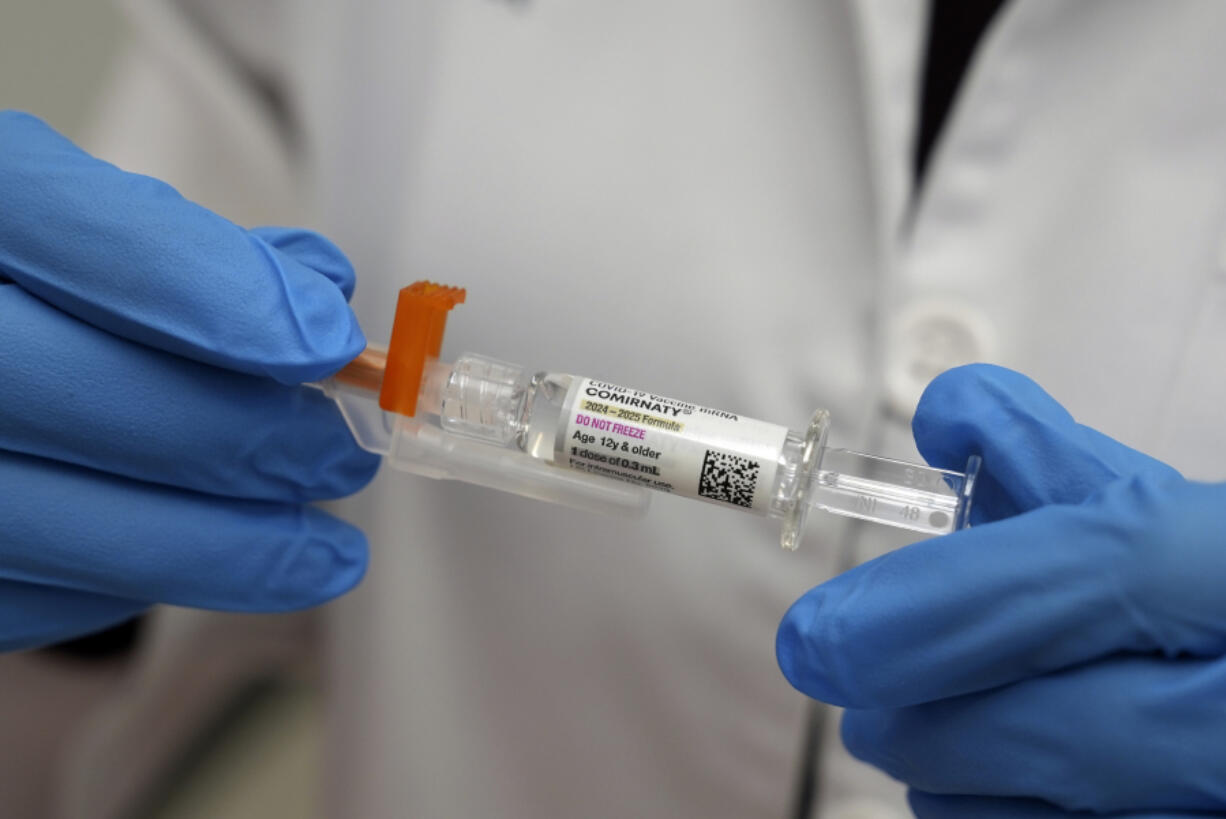 A pharmacist holds a COVID-19 vaccine at a pharmacy in New York, Tuesday, Sept. 24, 2024.