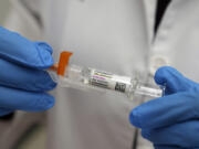 A pharmacist holds a COVID-19 vaccine at a pharmacy in New York, Tuesday, Sept. 24, 2024.