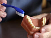 FILE - A dentist holds a model of teeth and a toothbrush in Seattle on Aug. 3, 2018.