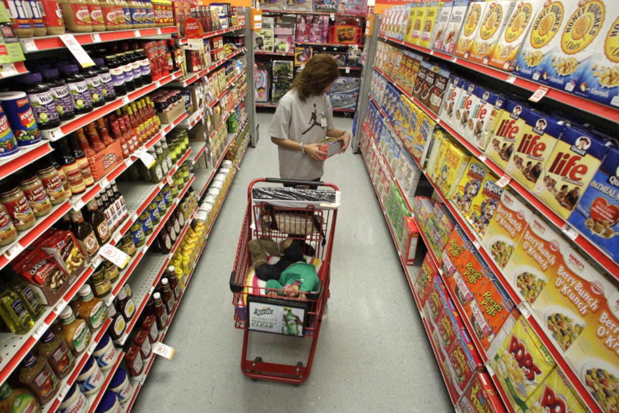 A woman looks at products in the aisle of a store as her daughter naps in a shopping cart in Waco, Texas.