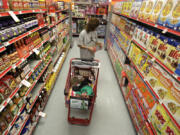 A woman looks at products in the aisle of a store as her daughter naps in a shopping cart in Waco, Texas.