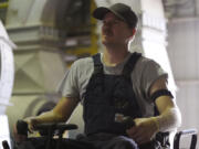 Wyatt Fischer, a furnace mason employee at Cardinal Glass, sits on an excavator while wearing a SlateSafety armband on Aug. 22 in Menomonie, Wis.