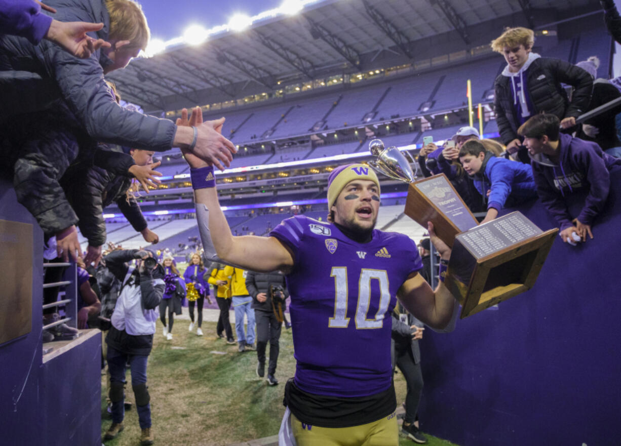 FILE - Washington quarterback Jacob Eason high fives fans as he leaves the field with the Apple Cup after an NCAA college football game against Washington State, Nov. 29, 2019 in Seattle.