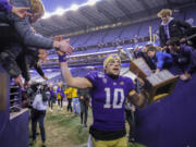 FILE - Washington quarterback Jacob Eason high fives fans as he leaves the field with the Apple Cup after an NCAA college football game against Washington State, Nov. 29, 2019 in Seattle.