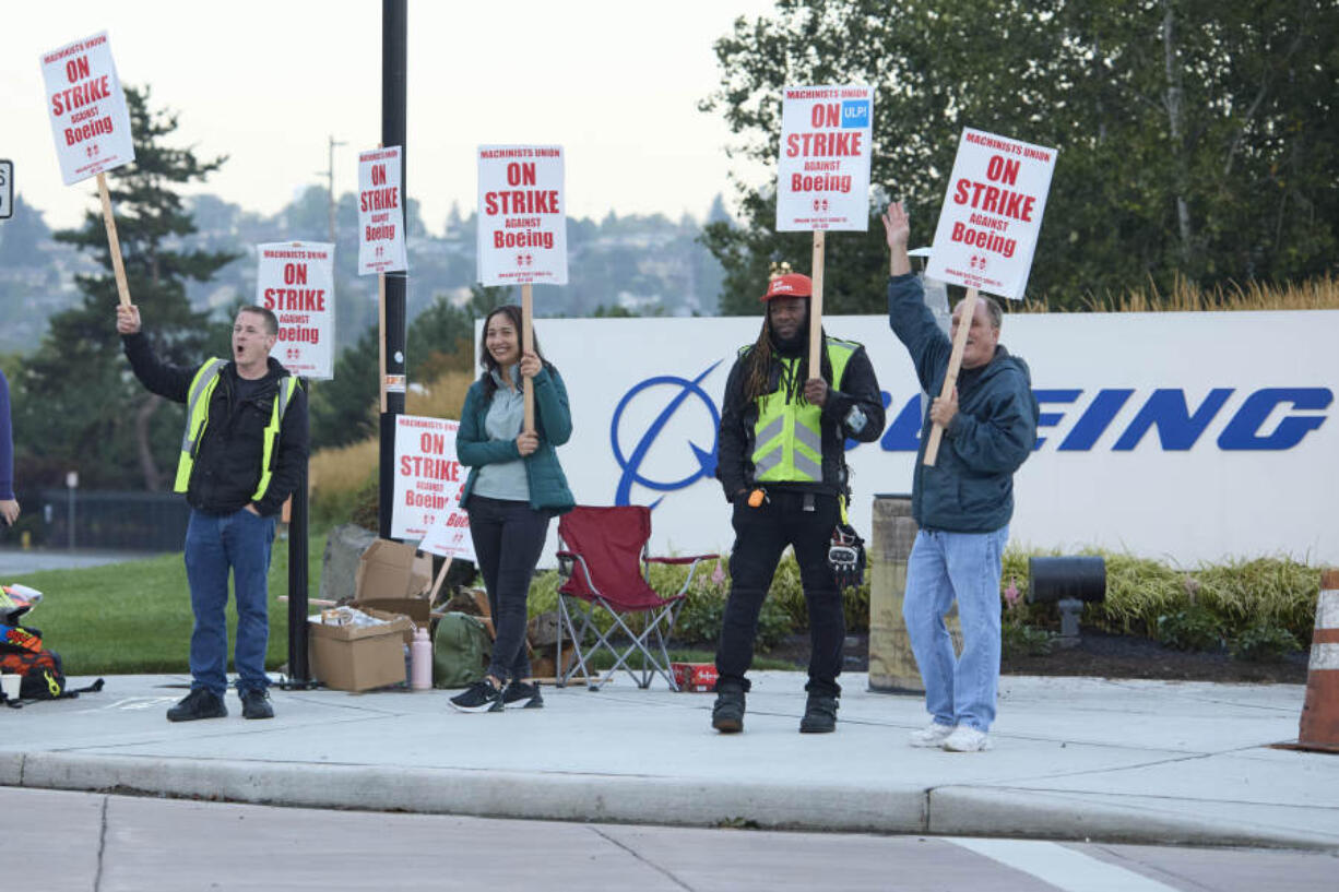 Boeing Machinists Union members from left, Brent Roberts, Ha Nguyen, Myles Simms and Rich Russell, wave to passing traffic while on the picket line at the Renton assembly plant, Friday, Sept. 13, 2024, in Renton, Wash.