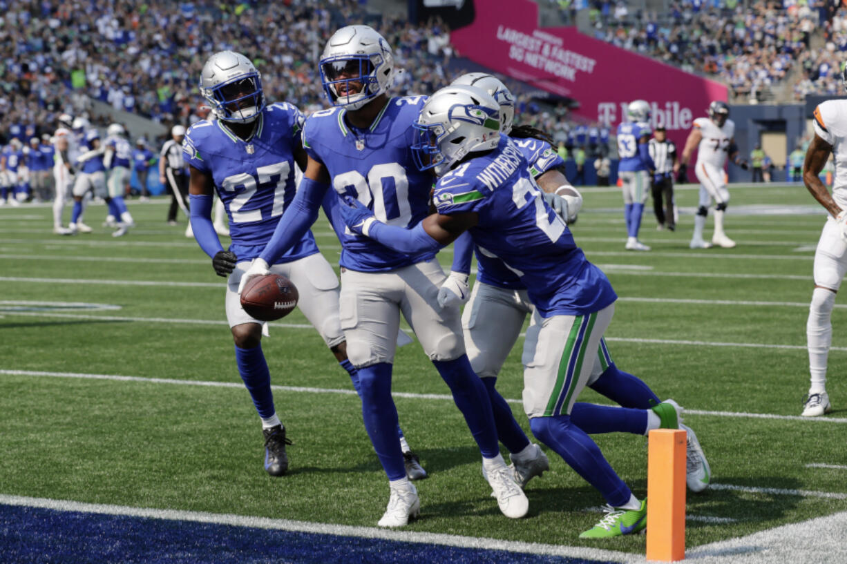 Seattle Seahawks safety Julian Love (20) is congratulated by cornerback Devon Witherspoon (21) and cornerback Riq Woolen (27) after intercepting a pass against the Denver Broncos during the first half of an NFL football game, Sunday, Sept. 8, 2024, in Seattle.