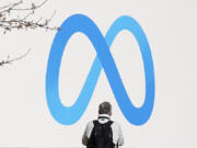 FILE - A person stands in front of a Meta sign outside of the company&#039;s headquarters in Menlo Park, Calif., March 7, 2023.