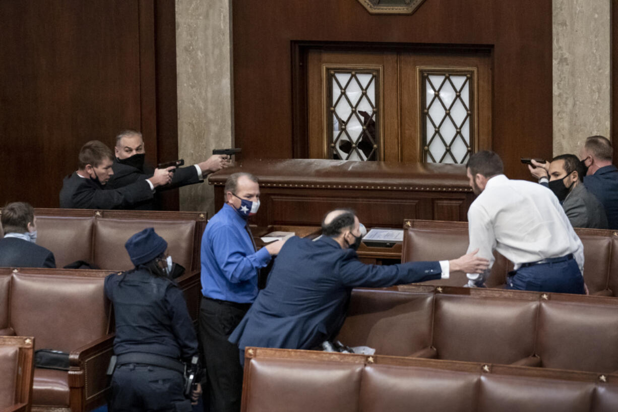 FILE - Security forces draw their guns as rioters loyal to President Donald Trump try to break into the House of Representatives chamber to disrupt the Electoral College process, at the Capitol in Washington,  Jan. 6, 2021.  (AP Photo/J.