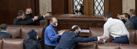 FILE - Security forces draw their guns as rioters loyal to President Donald Trump try to break into the House of Representatives chamber to disrupt the Electoral College process, at the Capitol in Washington,  Jan. 6, 2021.  (AP Photo/J.