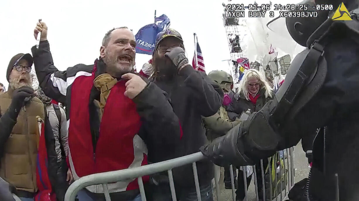 FILE- This still frame from Metropolitan Police Department body worn camera video shows Thomas Webster, in red jacket, at a barricade line at on the west front of the U.S. Capitol on Jan. 6, 2021, in Washington. Jurors deliberated for less than three hours before convicting the 20-year NYPD veteran, Thomas Webster, of all six counts in his indictment. Webster was sentenced to 10 years in prison.