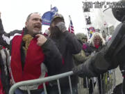 FILE- This still frame from Metropolitan Police Department body worn camera video shows Thomas Webster, in red jacket, at a barricade line at on the west front of the U.S. Capitol on Jan. 6, 2021, in Washington. Jurors deliberated for less than three hours before convicting the 20-year NYPD veteran, Thomas Webster, of all six counts in his indictment. Webster was sentenced to 10 years in prison.