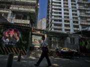 A man walks by a fruits vendor waiting for customers outside a luxury housing construction site in Beijing, Tuesday, Sept. 24, 2024.