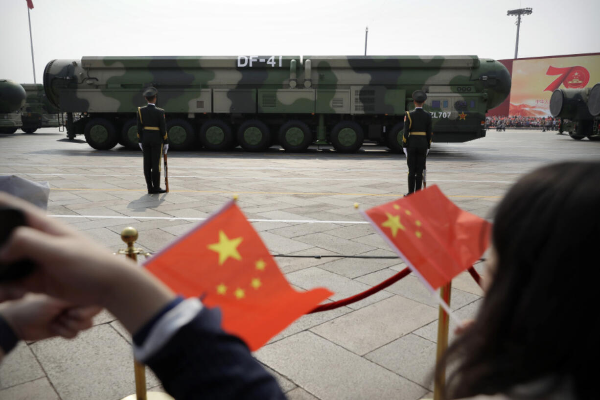 FILE - Spectators wave Chinese flags as military vehicles carrying DF-41 nuclear ballistic missiles roll during a parade to commemorate the 70th anniversary of the founding of Communist China in Beijing on Oct. 1, 2019.