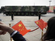 FILE - Spectators wave Chinese flags as military vehicles carrying DF-41 nuclear ballistic missiles roll during a parade to commemorate the 70th anniversary of the founding of Communist China in Beijing on Oct. 1, 2019.