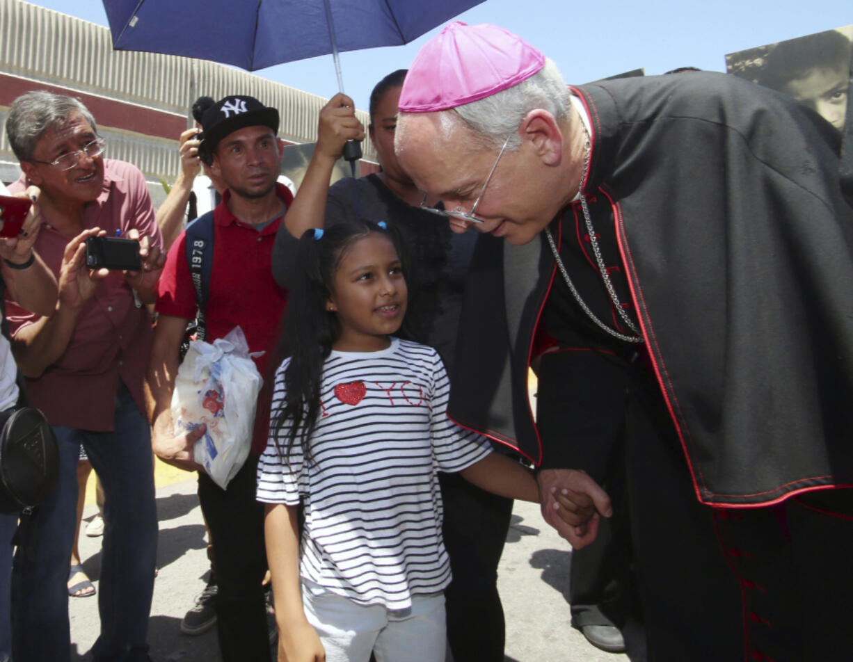 El Paso Catholic Bishop Mark Seitz talks with Celsia Palma, 9, of Honduras, as they walked June 27, 2019, to the Paso Del Norte International Port of Entry in Juarez, Mexico.