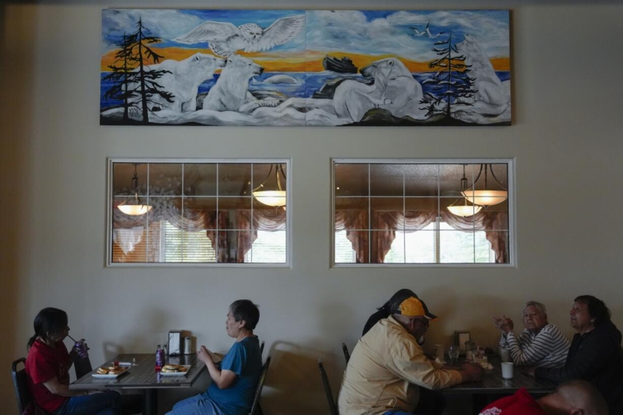 Patrons eat lunch below a mural depicting polar bears and other wildlife, Monday, Aug. 5, 2024, at the Seaport Hotel in Churchill, Manitoba. (AP Photo/Joshua A.