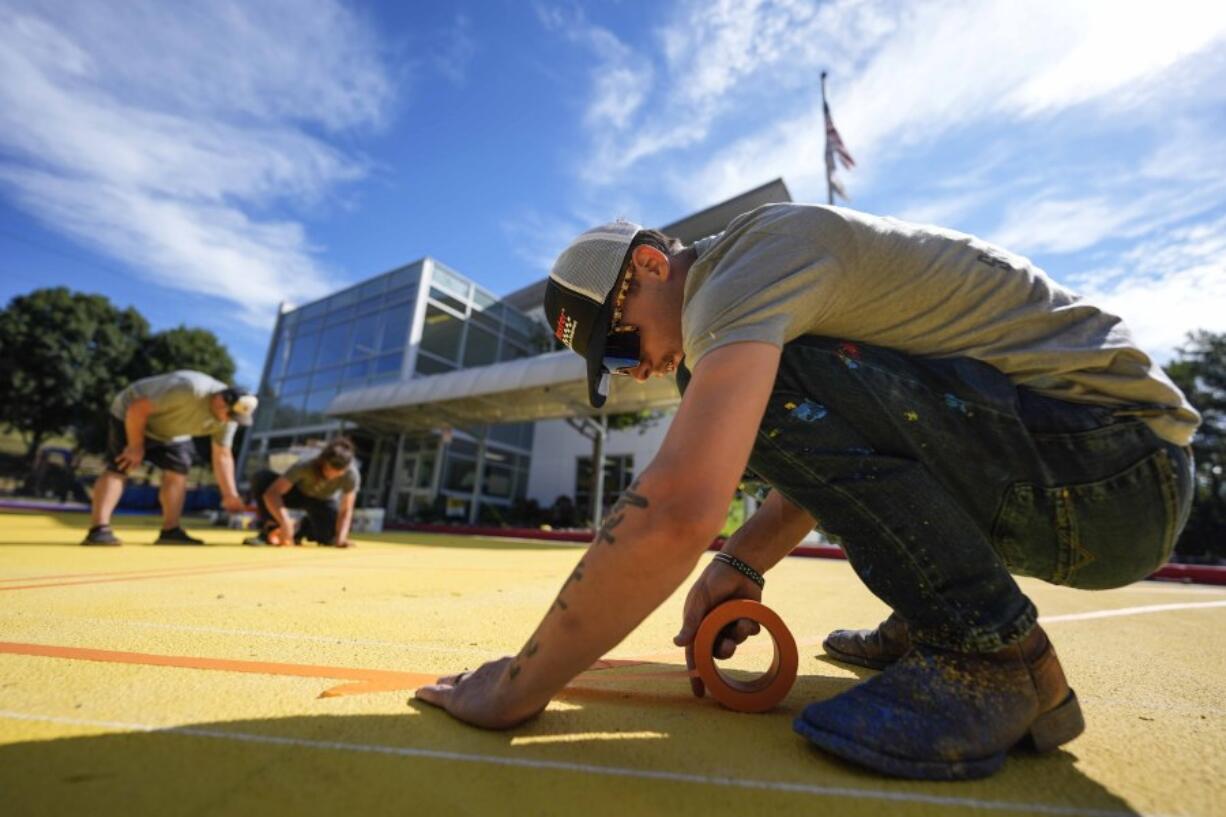 Ronnie Jefferies works on the parking lot at Science, Arts and Entrepreneurship School where it is being repainted to help cool it by making it more reflective Sept. 4 in Mableton, Ga.