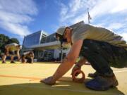 Ronnie Jefferies works on the parking lot at Science, Arts and Entrepreneurship School where it is being repainted to help cool it by making it more reflective Sept. 4 in Mableton, Ga.