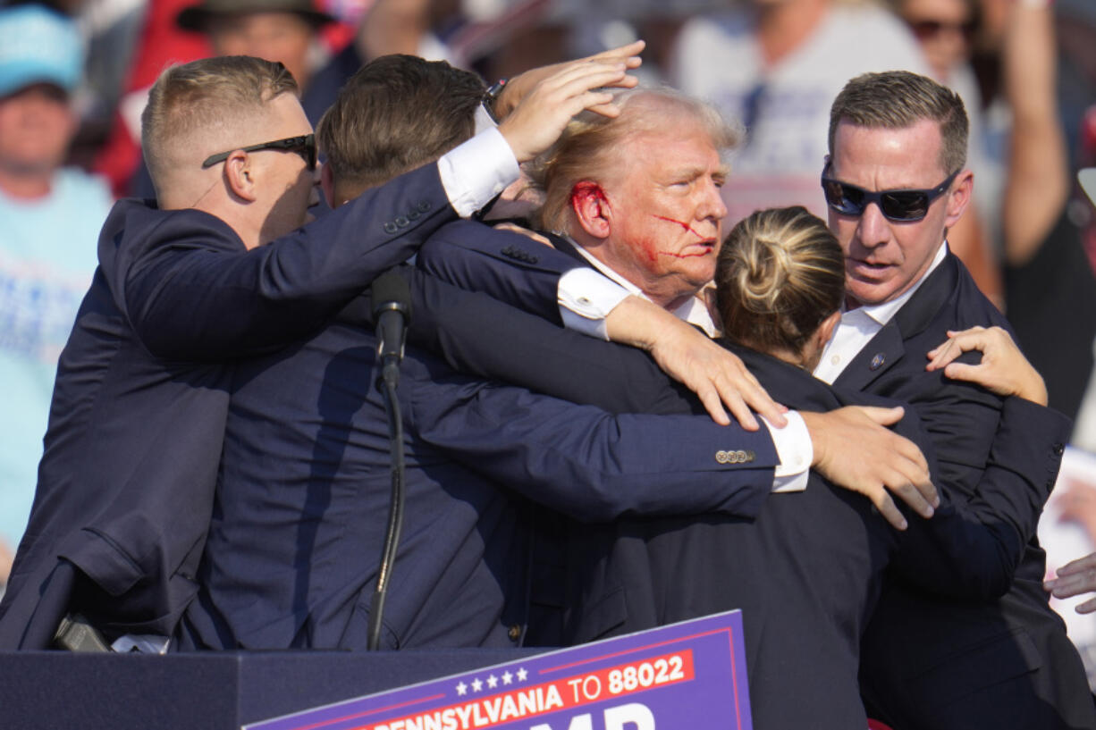 FILE - Republican presidential candidate former President Donald Trump is surrounded by U.S. Secret Service agents as he is helped off the stage at a campaign rally in Butler, Pa., July 13, 2024.  (AP Photo/Gene J.