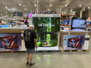 A shopper examines large-screen televisions on display in a Costco warehouse Thursday, Sept. 19, 2024, in Lone Tree, Colo.