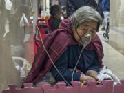 FILE - An elderly patient receives an intravenous drip while using a ventilator in the hallway of the emergency ward in Beijing, Thursday, Jan. 5, 2023.