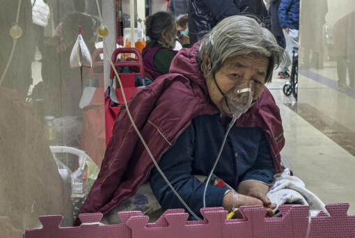 FILE - An elderly patient receives an intravenous drip while using a ventilator in the hallway of the emergency ward in Beijing, Thursday, Jan. 5, 2023.