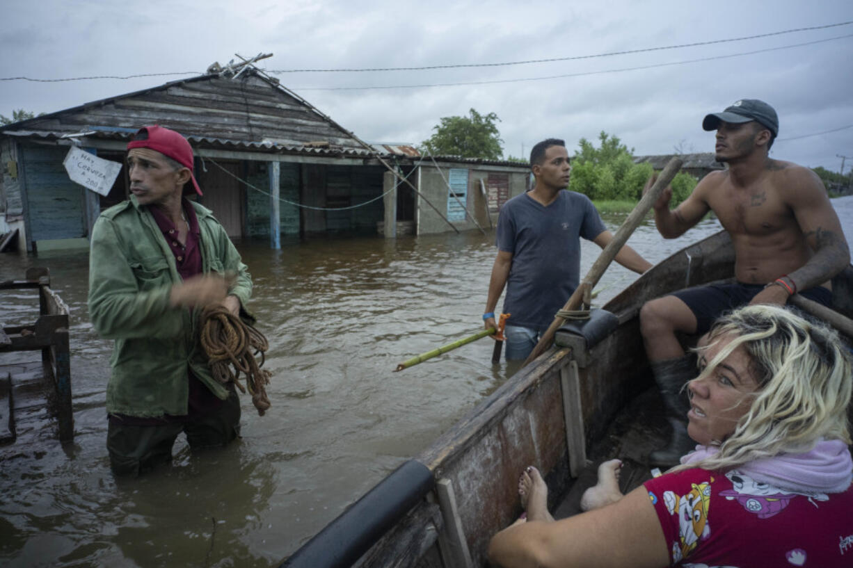 Neighbors chat on a flooded street after the passage of Hurricane Helene in Guanimar, Artemisa province, Cuba, Wednesday, Sept. 25, 2024.