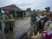 Neighbors chat on a flooded street after the passage of Hurricane Helene in Guanimar, Artemisa province, Cuba, Wednesday, Sept. 25, 2024.