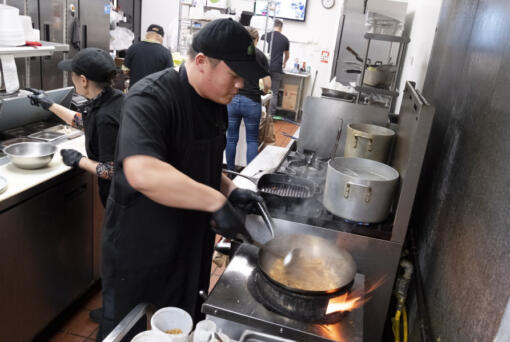 FILE - Tito Thepkaysone cooks up some pad Thai at &quot;Love &amp; Thai&quot; restaurant in Fresno, Calif., Wednesday, Dec. 20, 2023. The Thai restaurant was wrongfully accused of abusing a dog to turn it into meat, a false claim rooted in a racist stereotype.