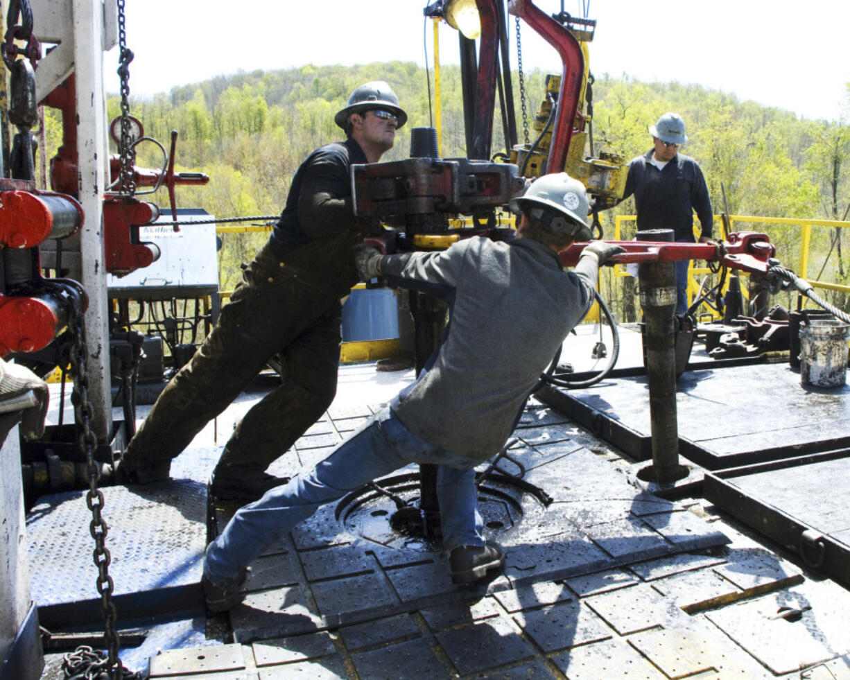 FILE - Workers move a section of well casing into place at a Chesapeake Energy natural gas well site near Burlington, Pa., in Bradford County, on April 23, 2010.