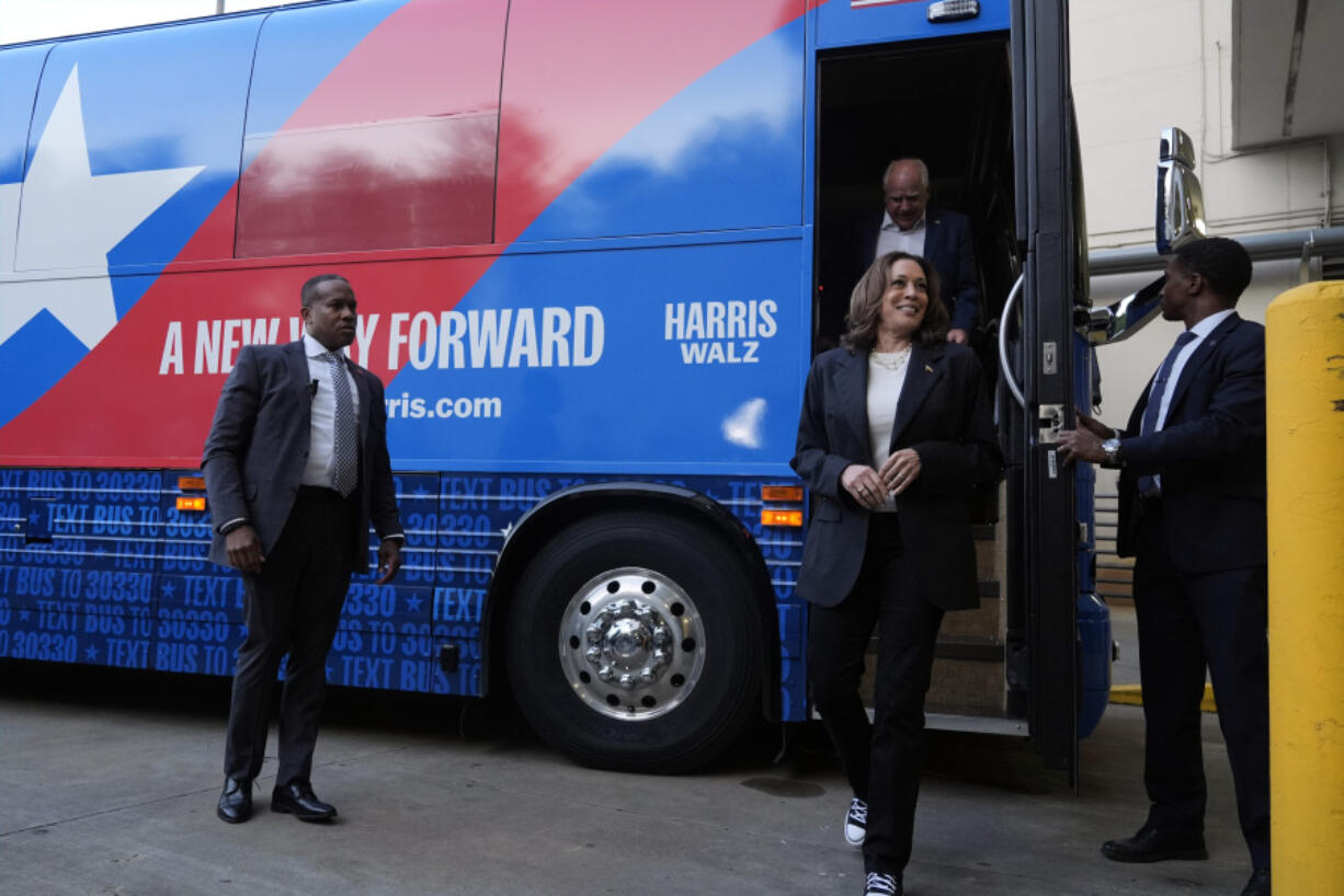 Democratic presidential nominee Vice President Kamala Harris and her running mate Minnesota Gov. Tim Walz exit their campaign bus in Savannah, Ga., Wednesday, Aug. 28, 2024.