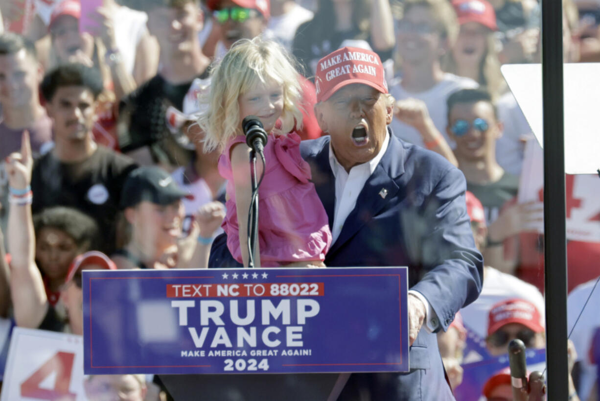 Republican presidential nominee former President Donald Trump holds his granddaughter Carolina Trump as he speaks at a campaign event at Wilmington International Airport in Wilmington, N.C., Saturday, Sept. 21, 2024.