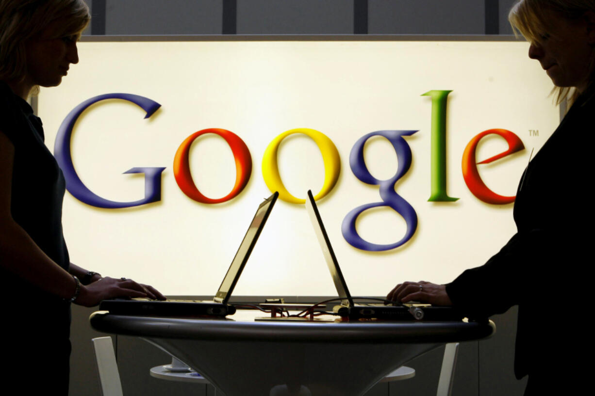 In this April 17, 2007 file photo, exhibitors work on laptop computers in front of an illuminated sign of the Google logo at the industrial fair Hannover Messe in Hanover, Germany.