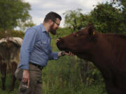 Farmer and Presbyterian pastor Lee Scott pets one of the cows Sept. 6 on his family farm, Laurel Oak Farm, in Butler, Pa.