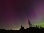 FILE - In this image taken with a long exposure, people look at the night sky towards the northern lights, or Aurora Borealis, May 10, 2024, in Estacada, Ore.