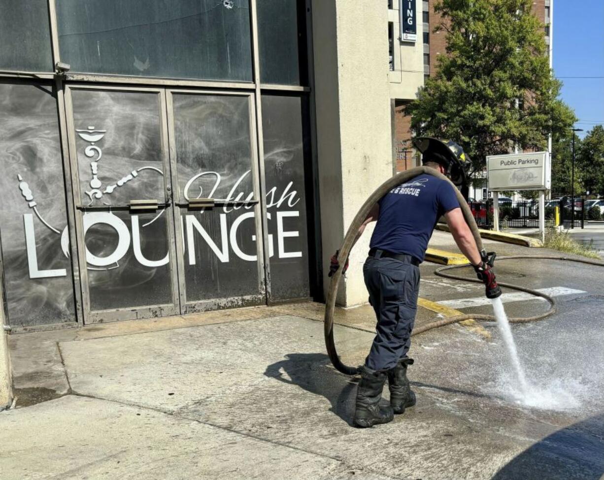 A firefighter cleans blood stains off the sidewalk outside a nightclub in Birmingham, Ala. on Sunday, Sept. 22, 2024, after a mass shooting took place.