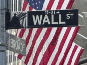 FILE - Signs at the intersection of Broad and Wall Streets stand near flags flying from the New York Stock Exchange on Sept. 4, 2024, in New York.