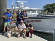 In this undated photo provided by Atlantic Wreck Salvage, members the Discovery team pose in New Bedford, Mass., on Sunday, Aug. 25, 2024. with portholes recovered from the passenger steamship Le Lyonnais.