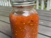 A jar of cooked tomatoes with basil ready for the freezer.